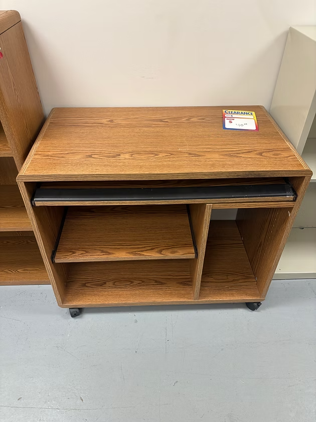 Wooden computer cart with pull-out keyboard tray and shelves, on casters, indoors.