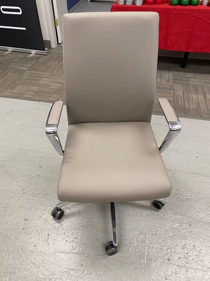Tan office chair with chrome arms and base; on a concrete floor.