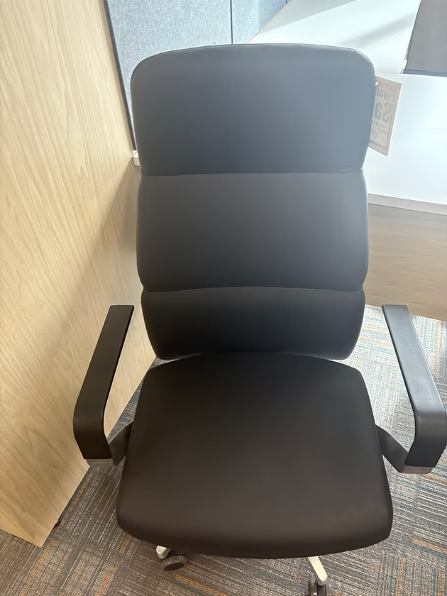 Black office chair with armrests in a room.