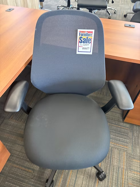 Gray office chair with mesh back and padded seat, sticker reading