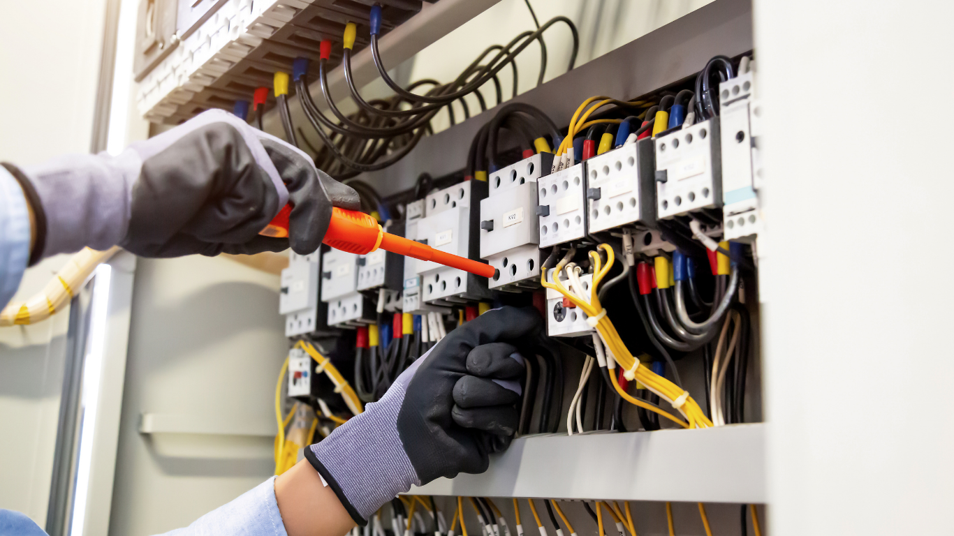 Electrician inspecting electrical panel with a voltage tester.