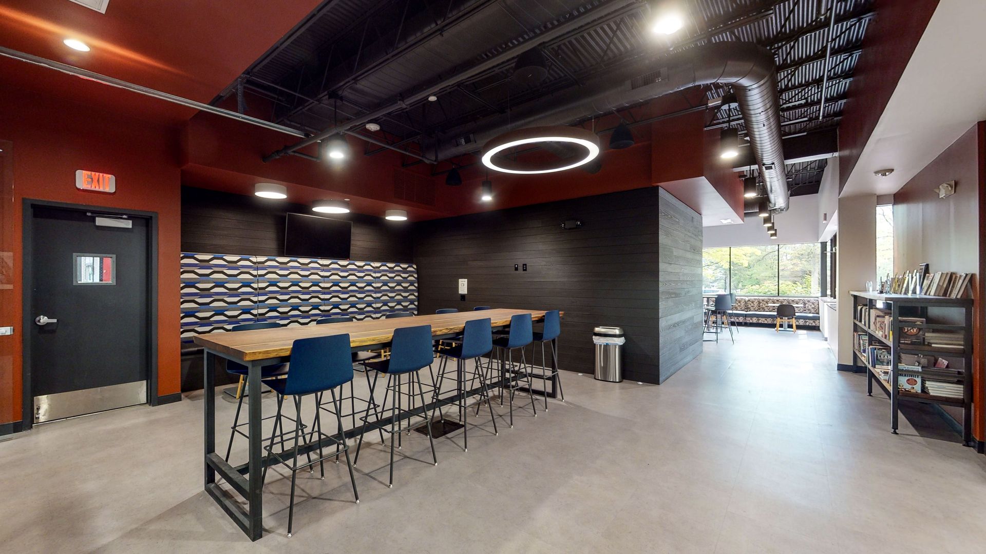 Modern break room with a long table, blue chairs, and a dark color scheme.