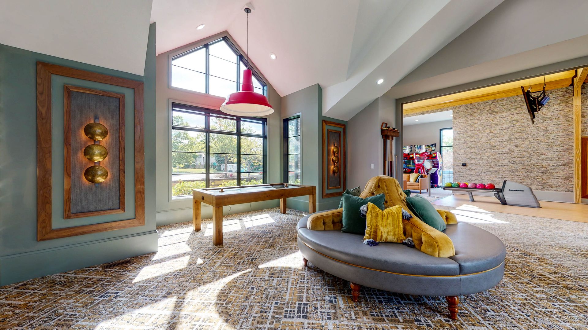 Lobby with seating, large window, and decorative wall panels. A red pendant lamp hangs above the wooden table.