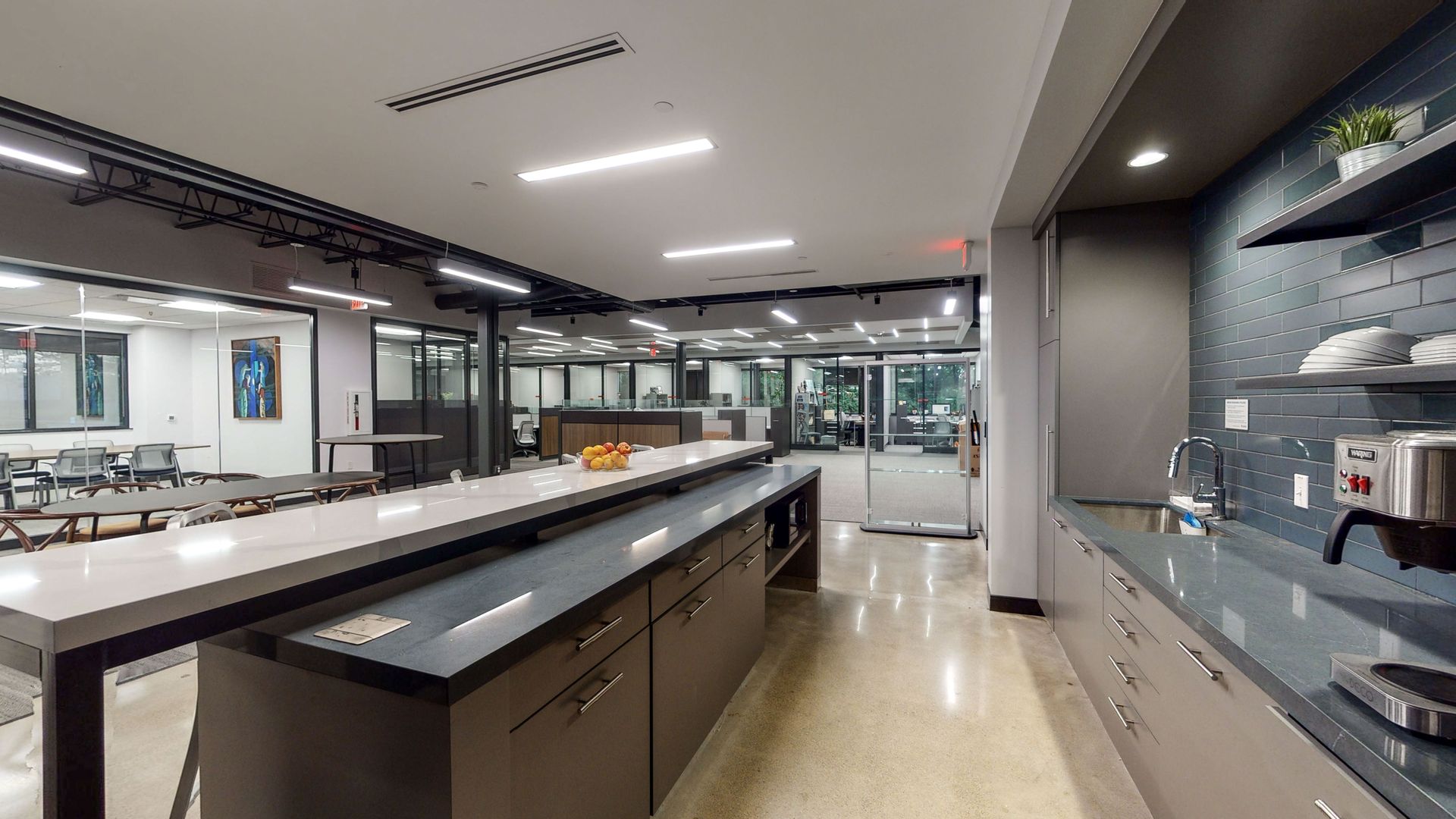 Modern office kitchen with long island, countertops, and seating areas.