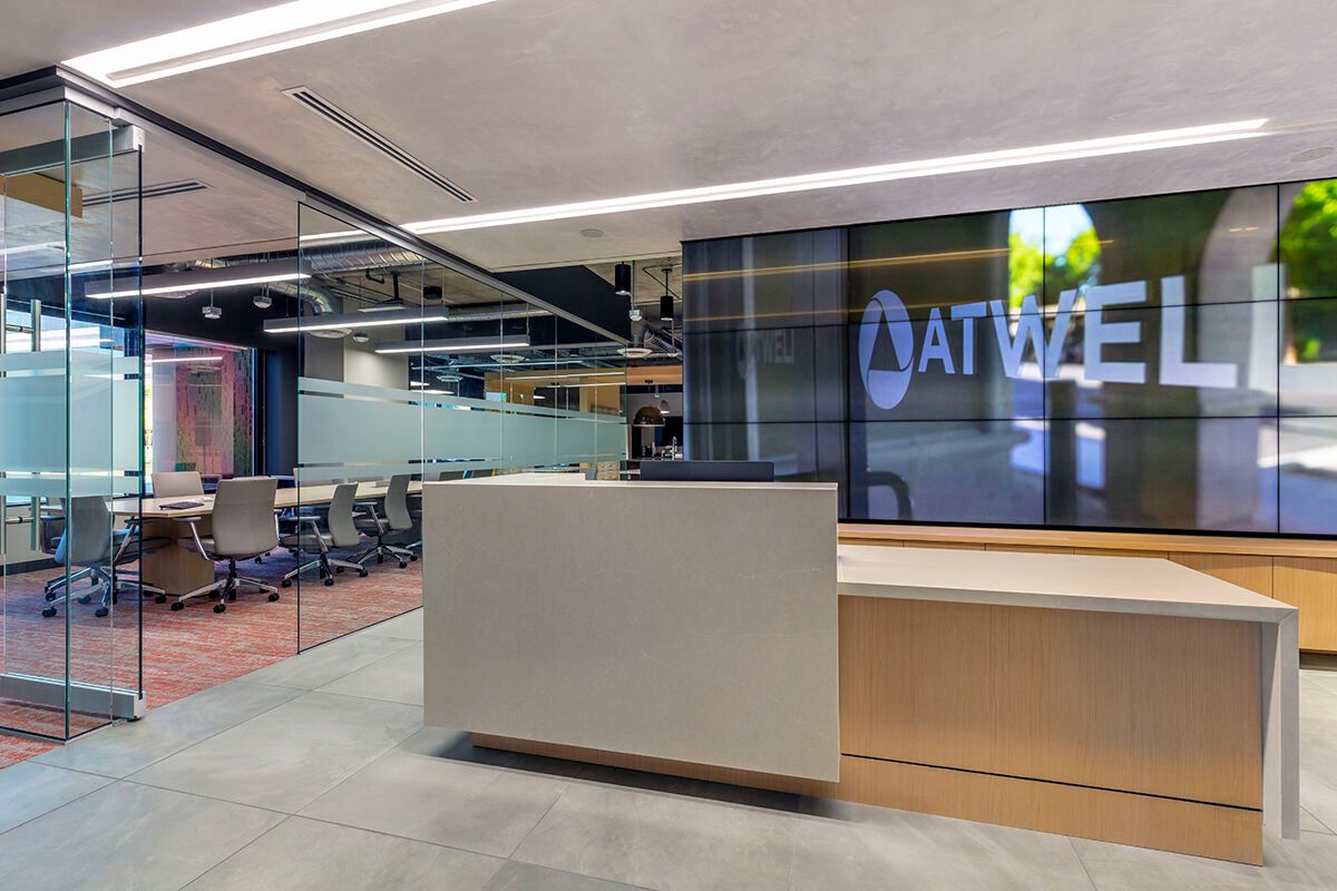 Modern office lobby with glass walls, reception desk, and ATWELL logo on the back wall