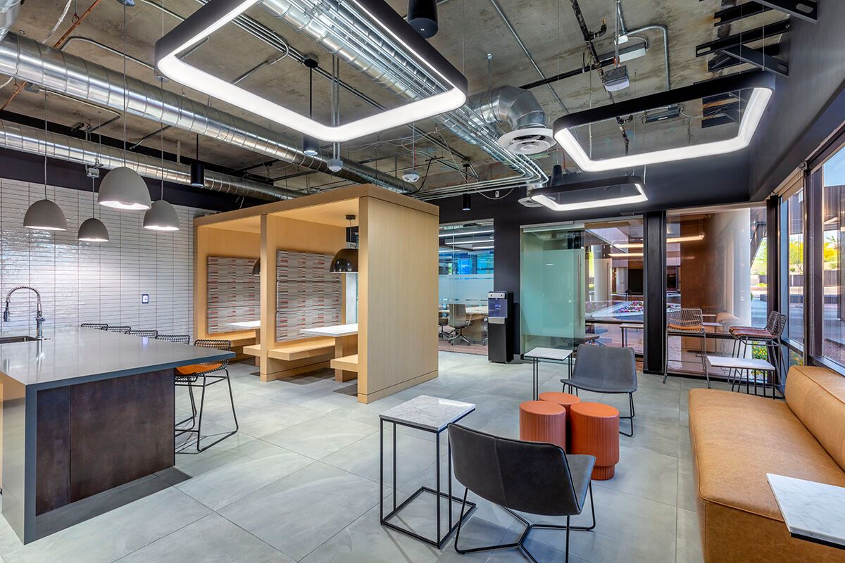 Modern co-working office with wood meeting pod, lounge seating, and exposed industrial ceiling