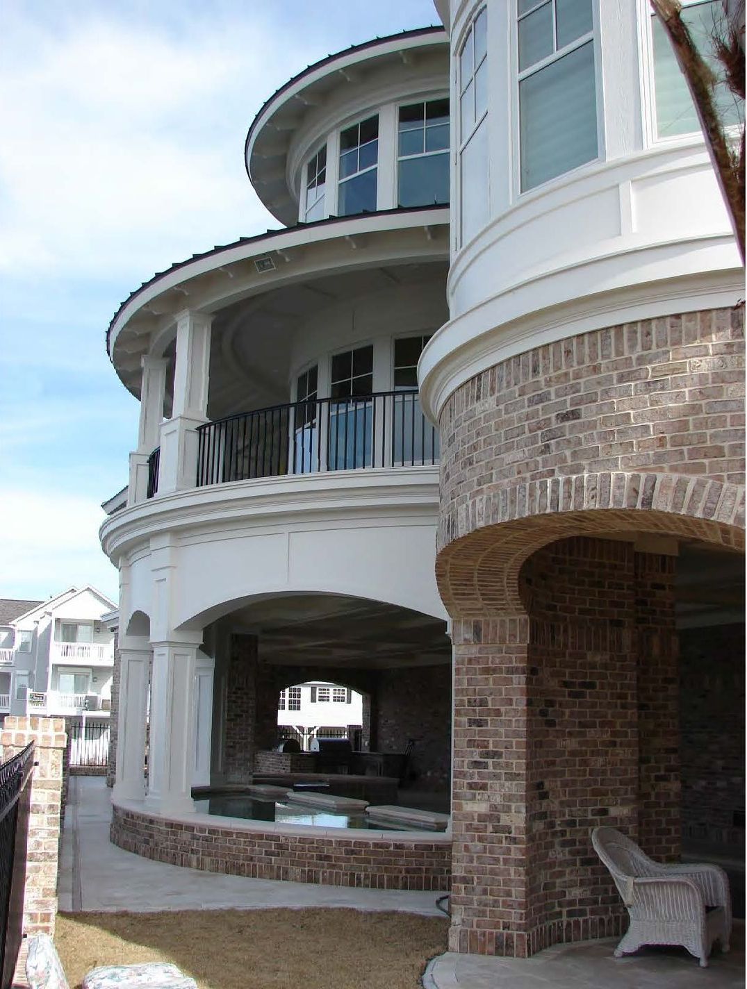 Multi-story, round-shaped house with brick and white facade, arched ground-level entrance.