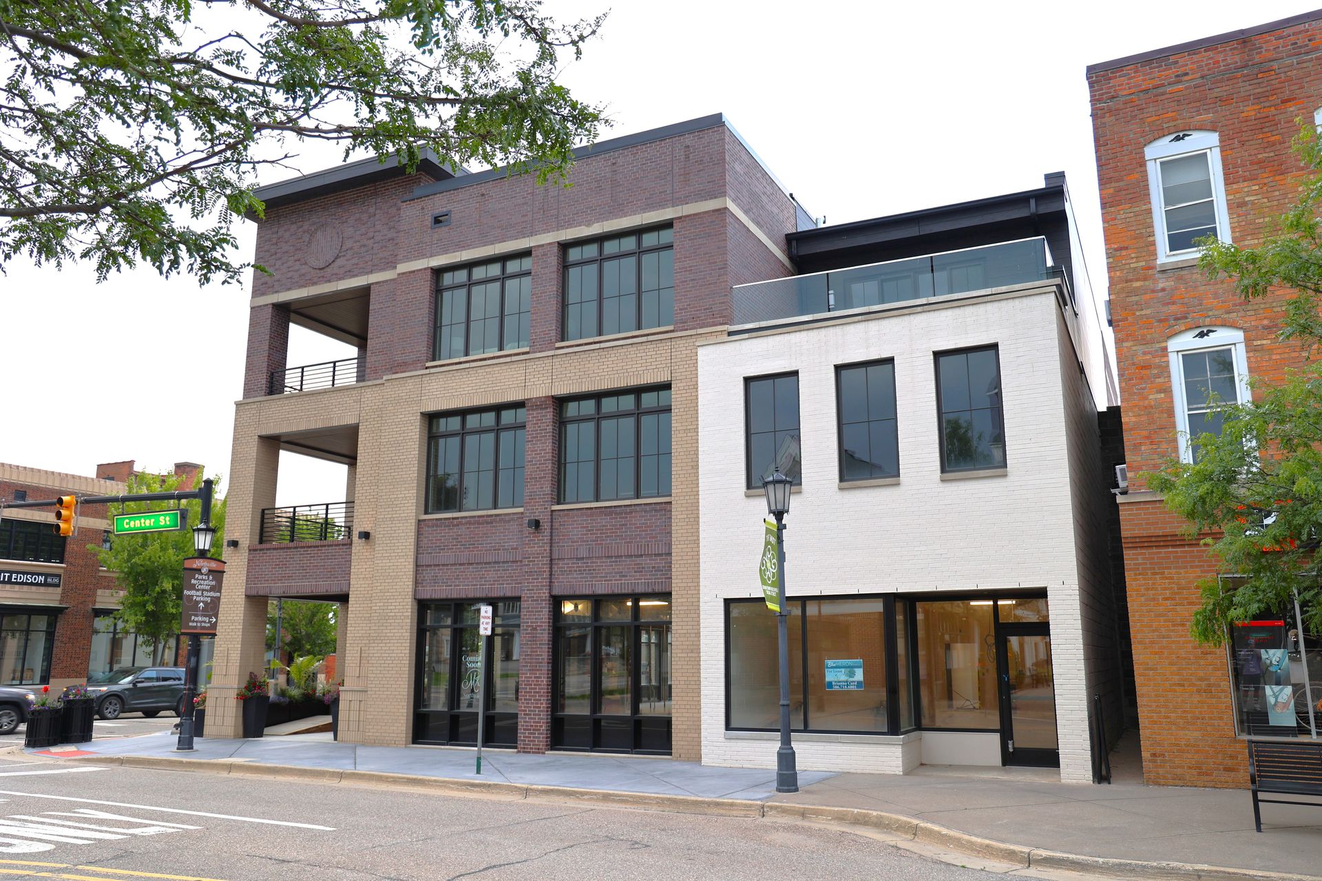 Buildings on a city street, with brick, tan, and white facades. A street sign is visible.