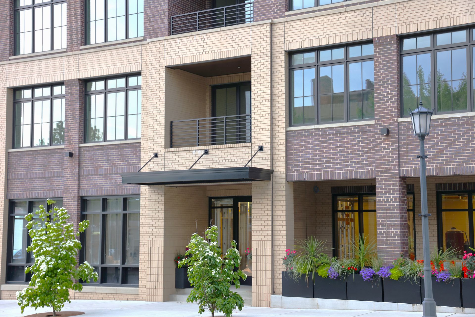 Brick building facade with windows, a small balcony, and a dark awning.