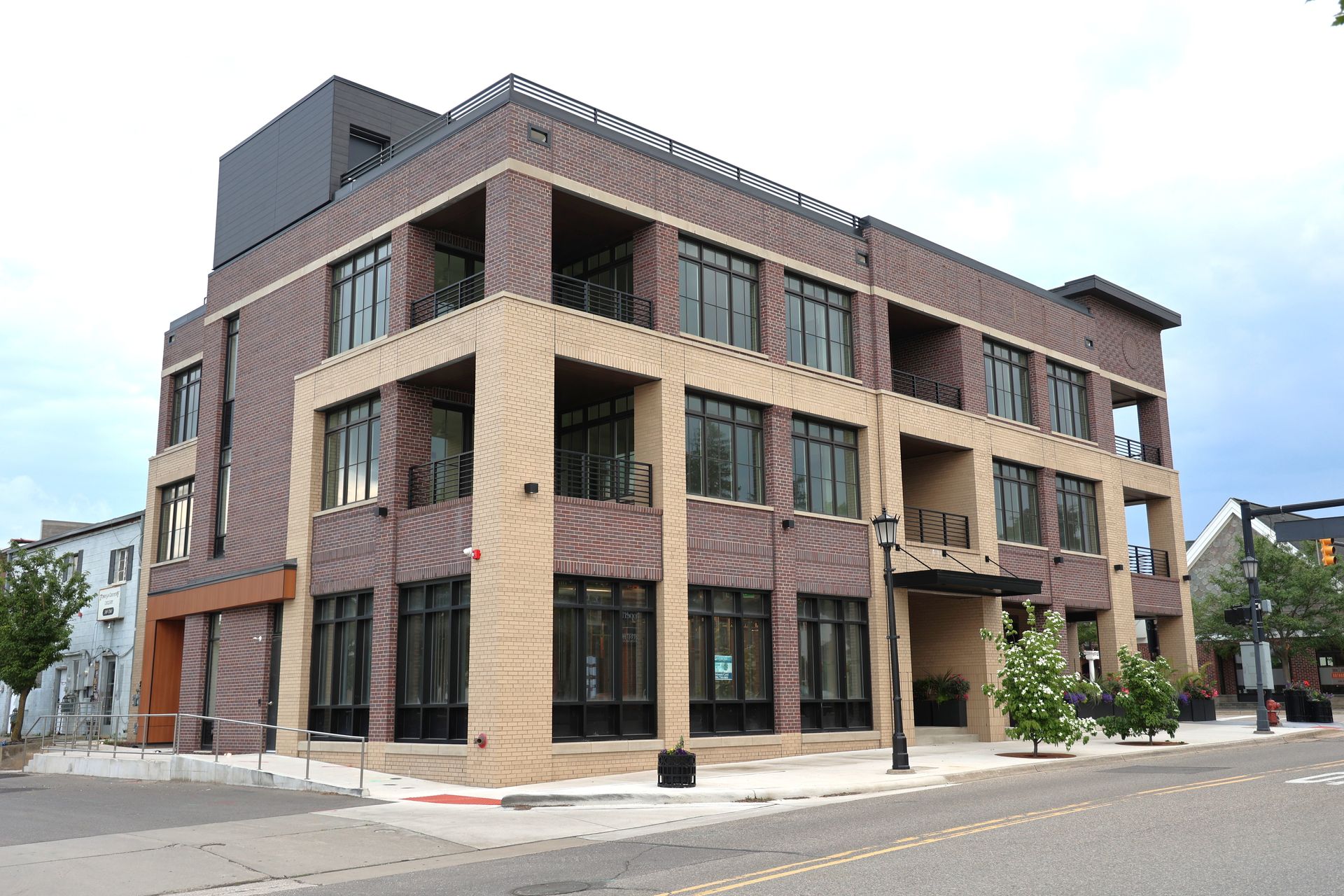 Brick and beige commercial building with large windows and dark trim on a city street.