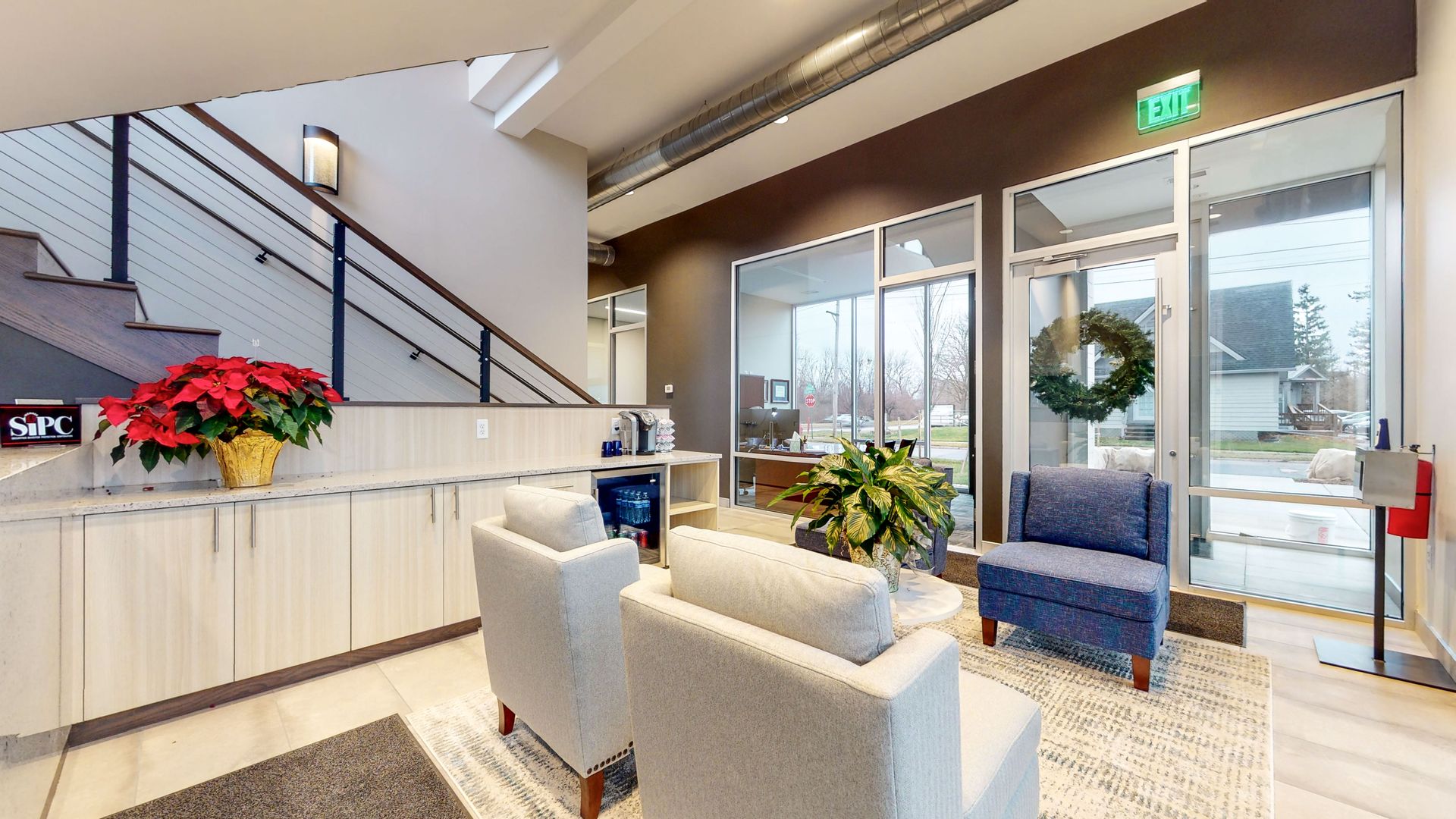 Lobby with seating, poinsettias, and staircase. Windows with view of street.