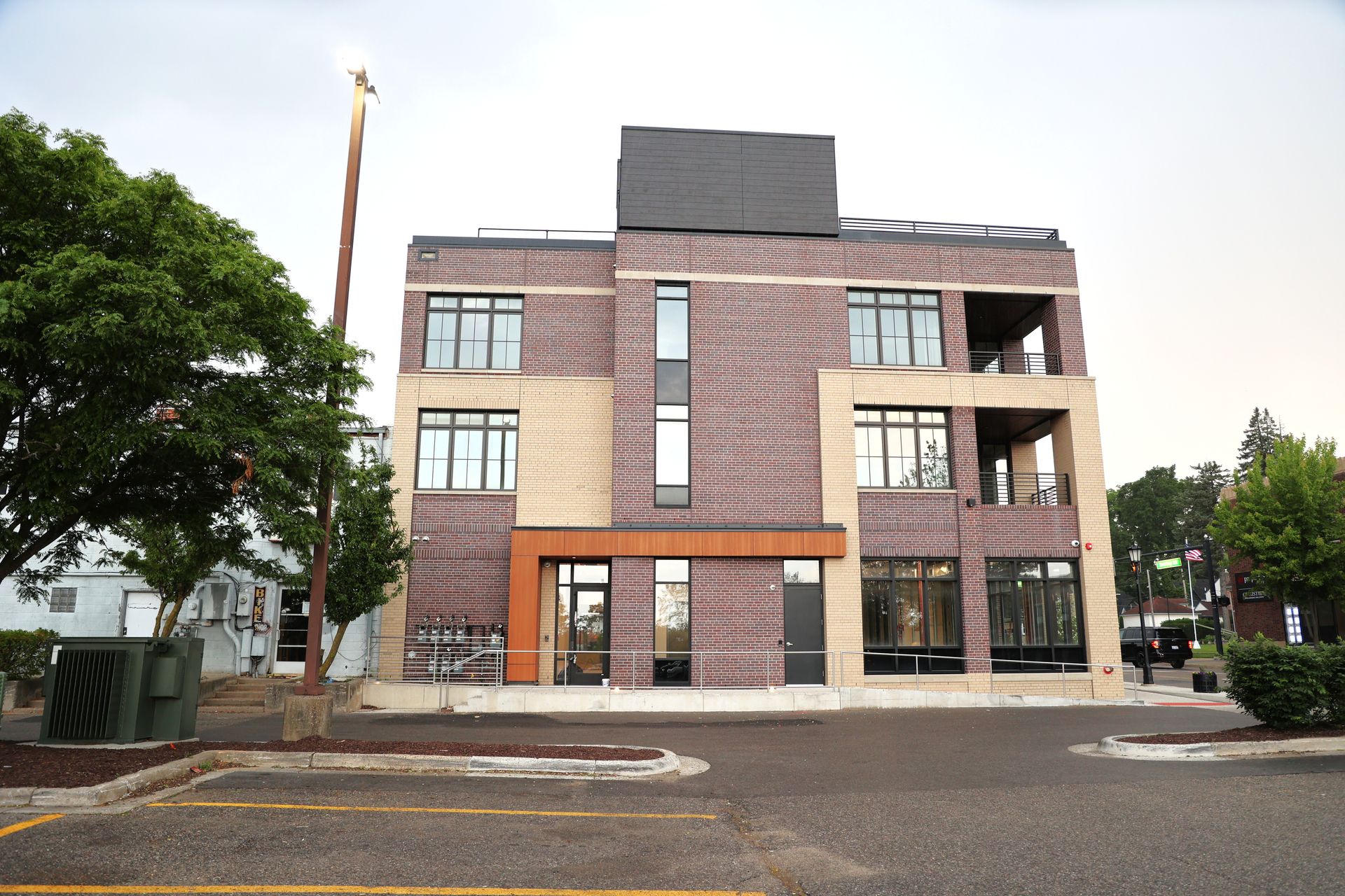 Modern brick building with balconies and large digital screen on the roof.