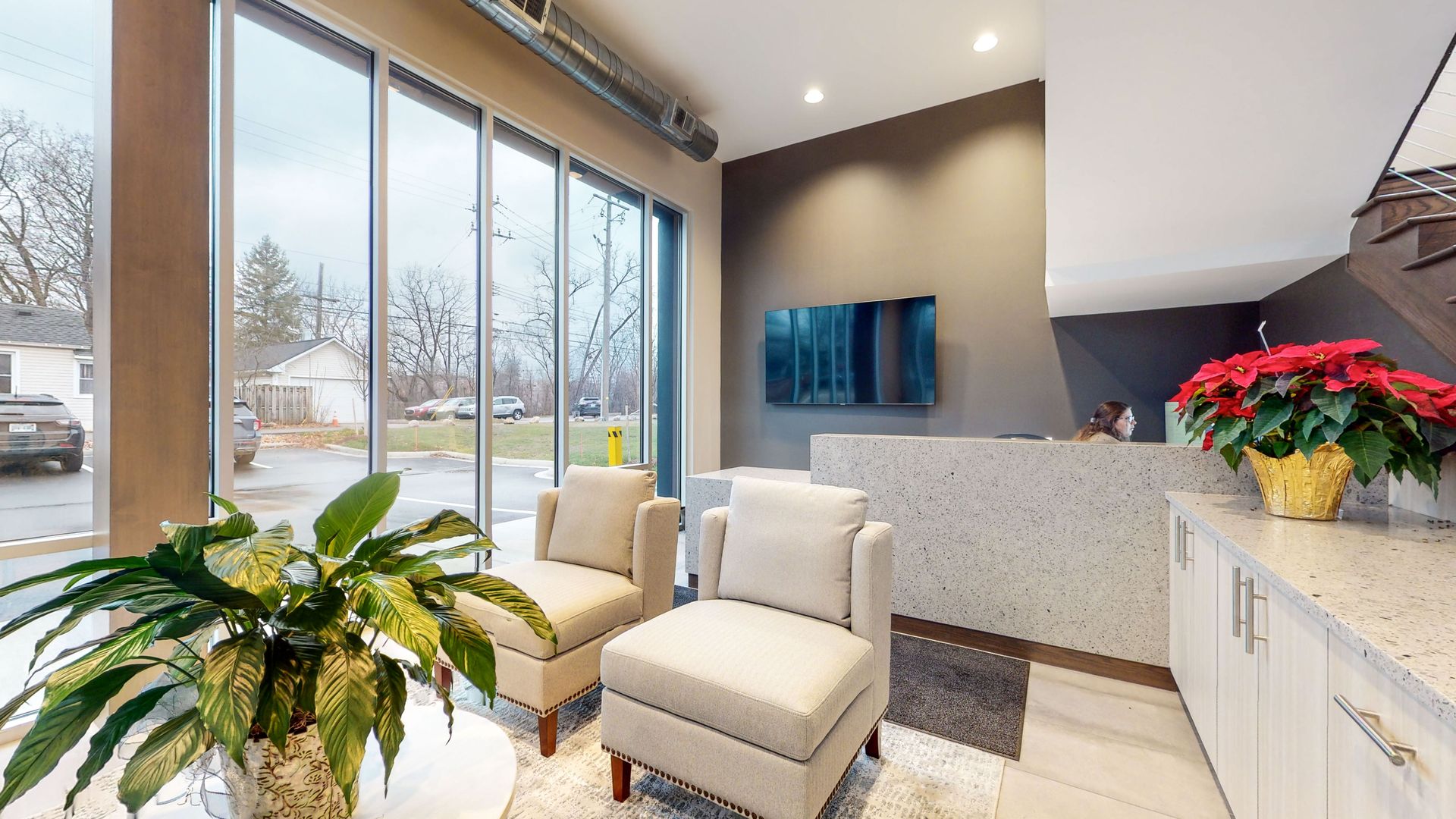 Waiting area with two chairs, reception desk, and large window with outdoor view.