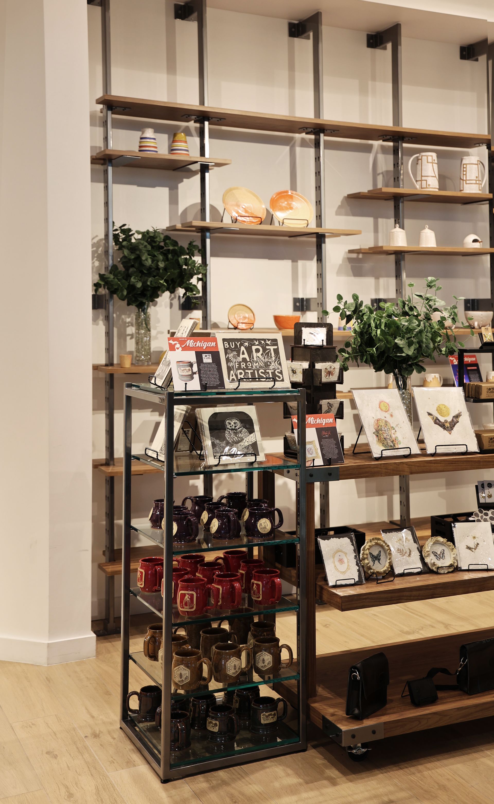 Retail display with wooden shelves, mugs, and other items for sale.