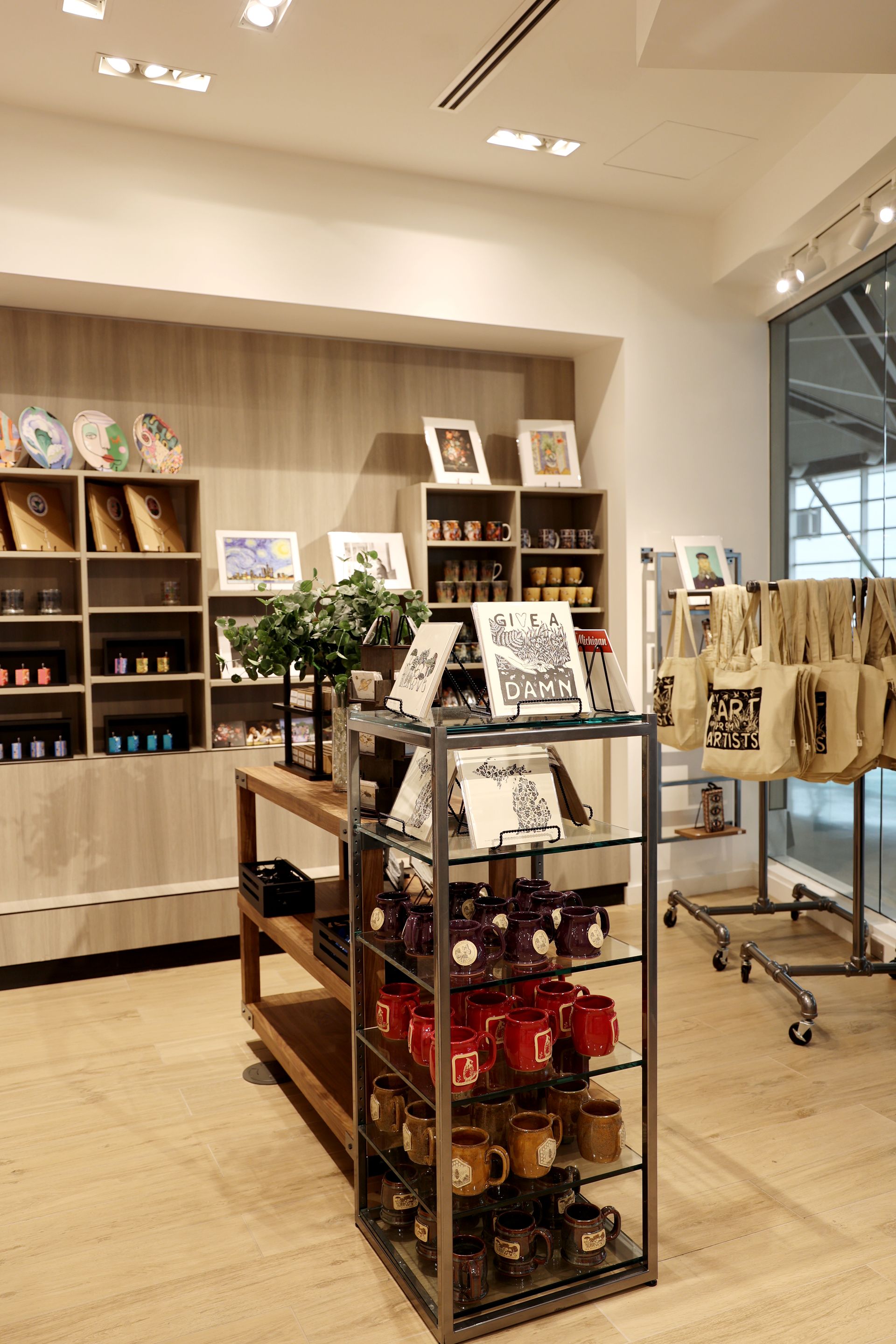 Gift shop interior with shelves displaying products, including mugs, plates, and tote bags.