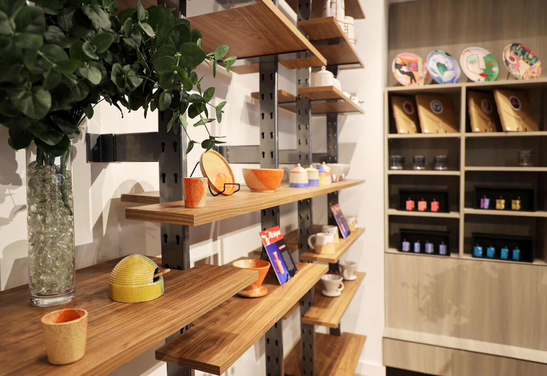 Wooden shelves displaying ceramics in a shop, with colorful plates and other items.