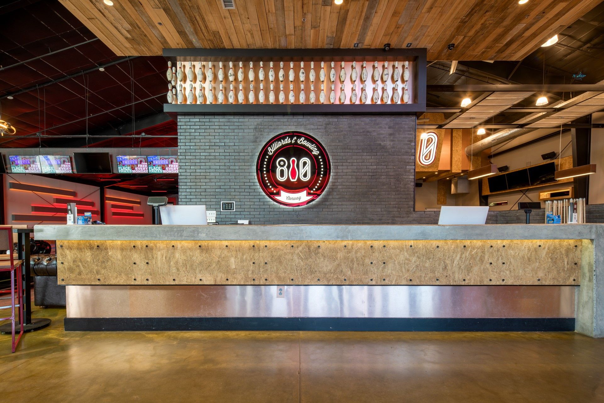 Reception desk at a restaurant, with wood and copper accents. The restaurant name is displayed on the wall.