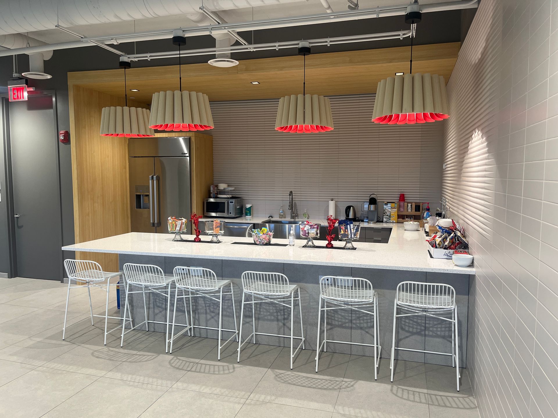 Modern bar with white stools, wood counters, pendant lights, and a back counter in a bright interior