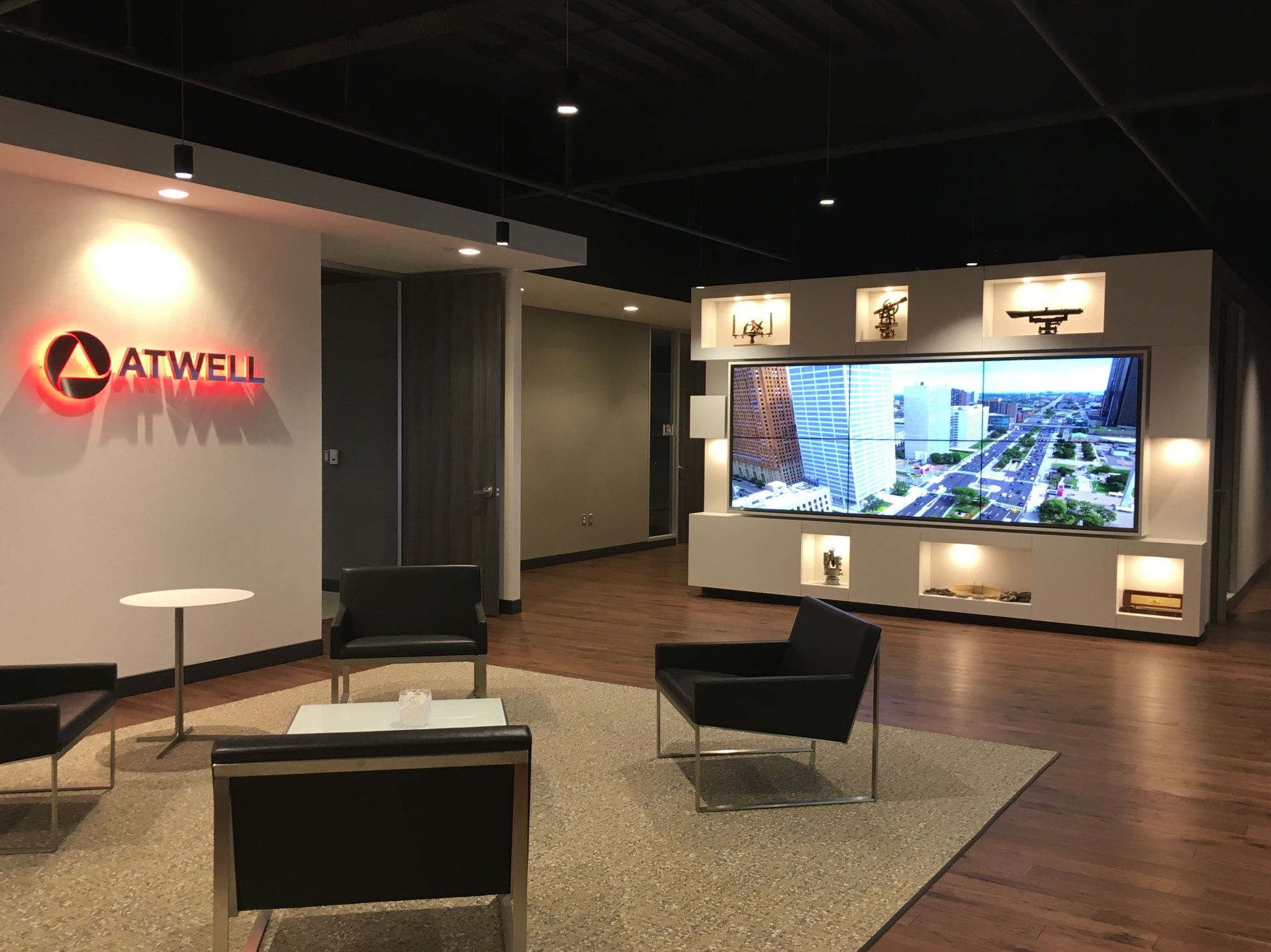 Modern office lounge with ATWELL logo, seating, and a large illuminated display wall