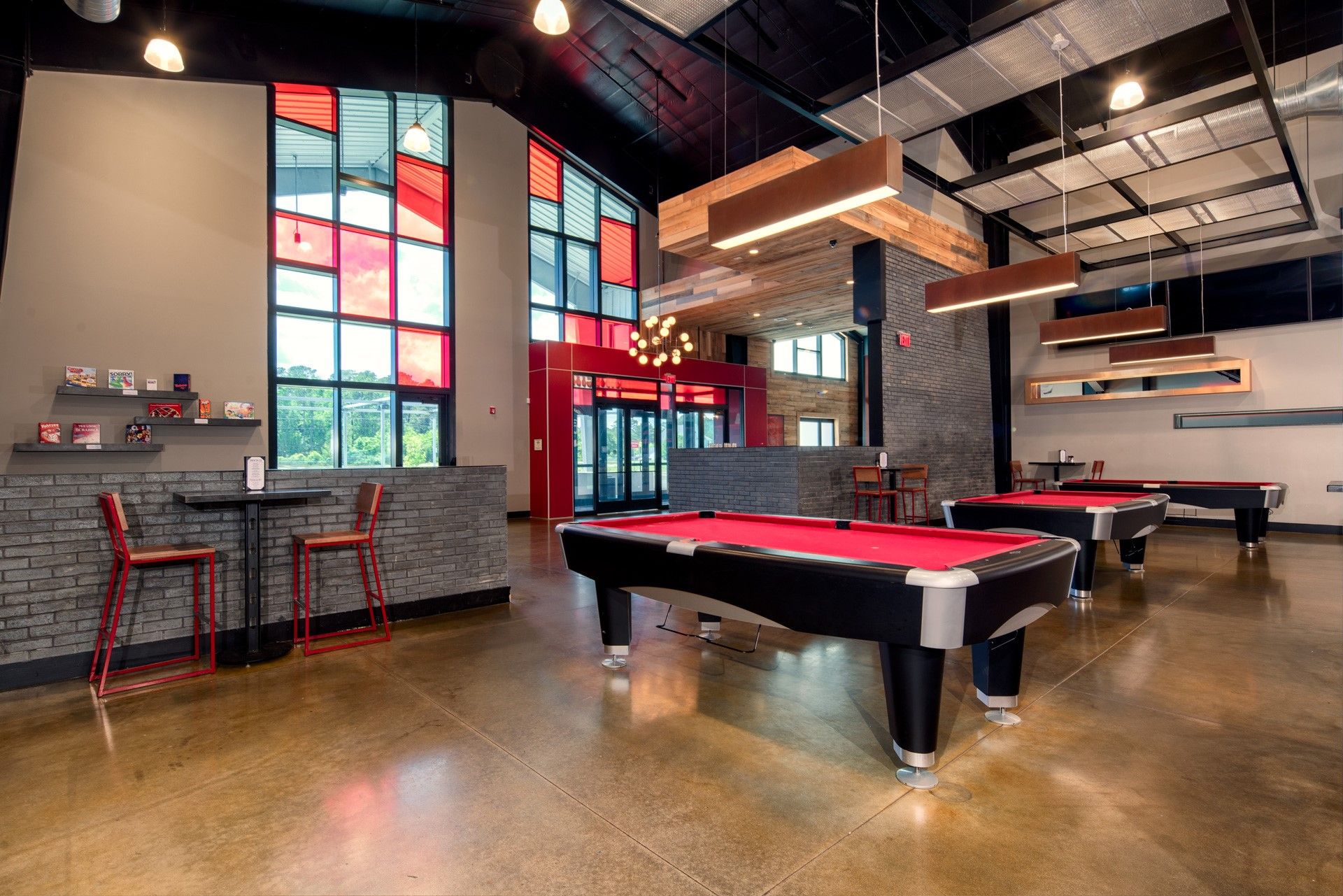 Game room with pool tables, red accents, and large windows.