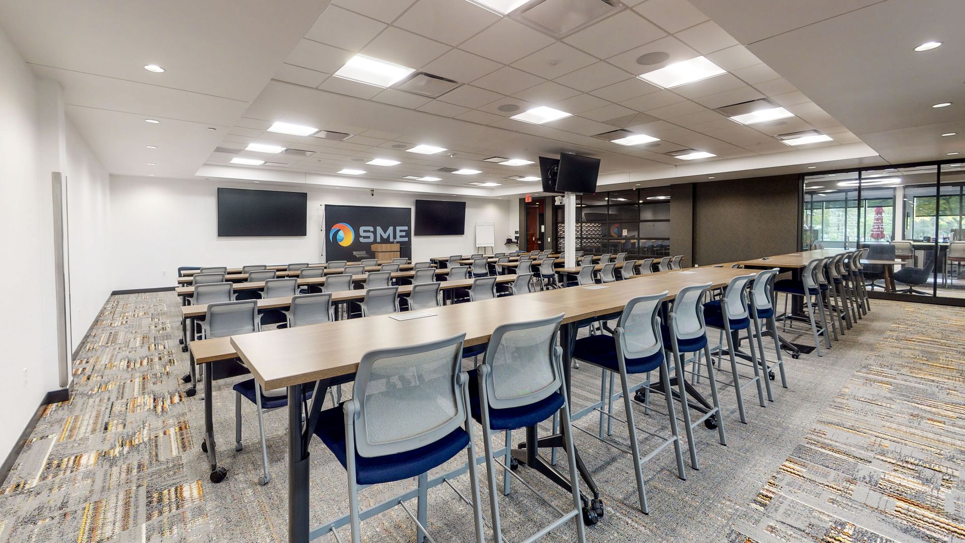 Empty classroom or training room with rows of tables and blue chairs under bright ceiling lights