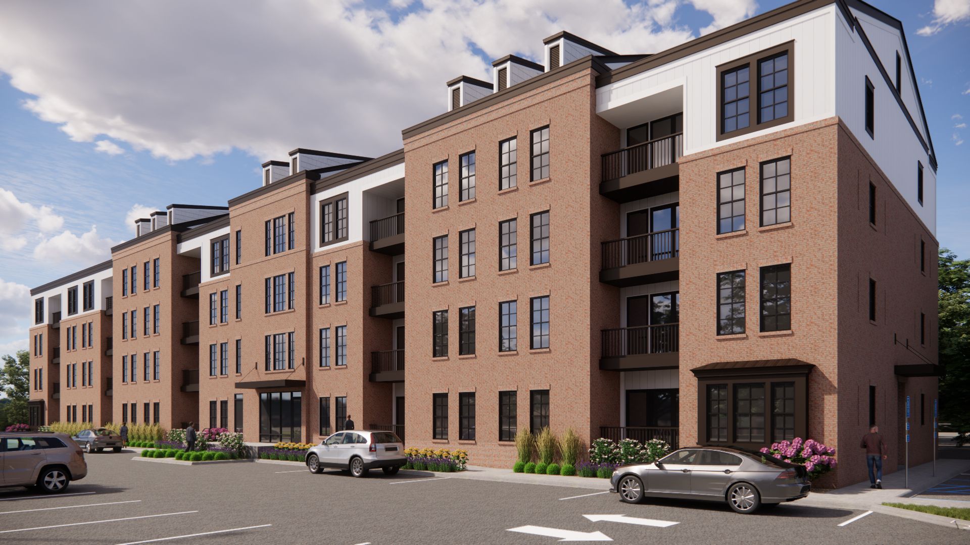 Multi-story brick apartment building with balconies and cars parked in front.