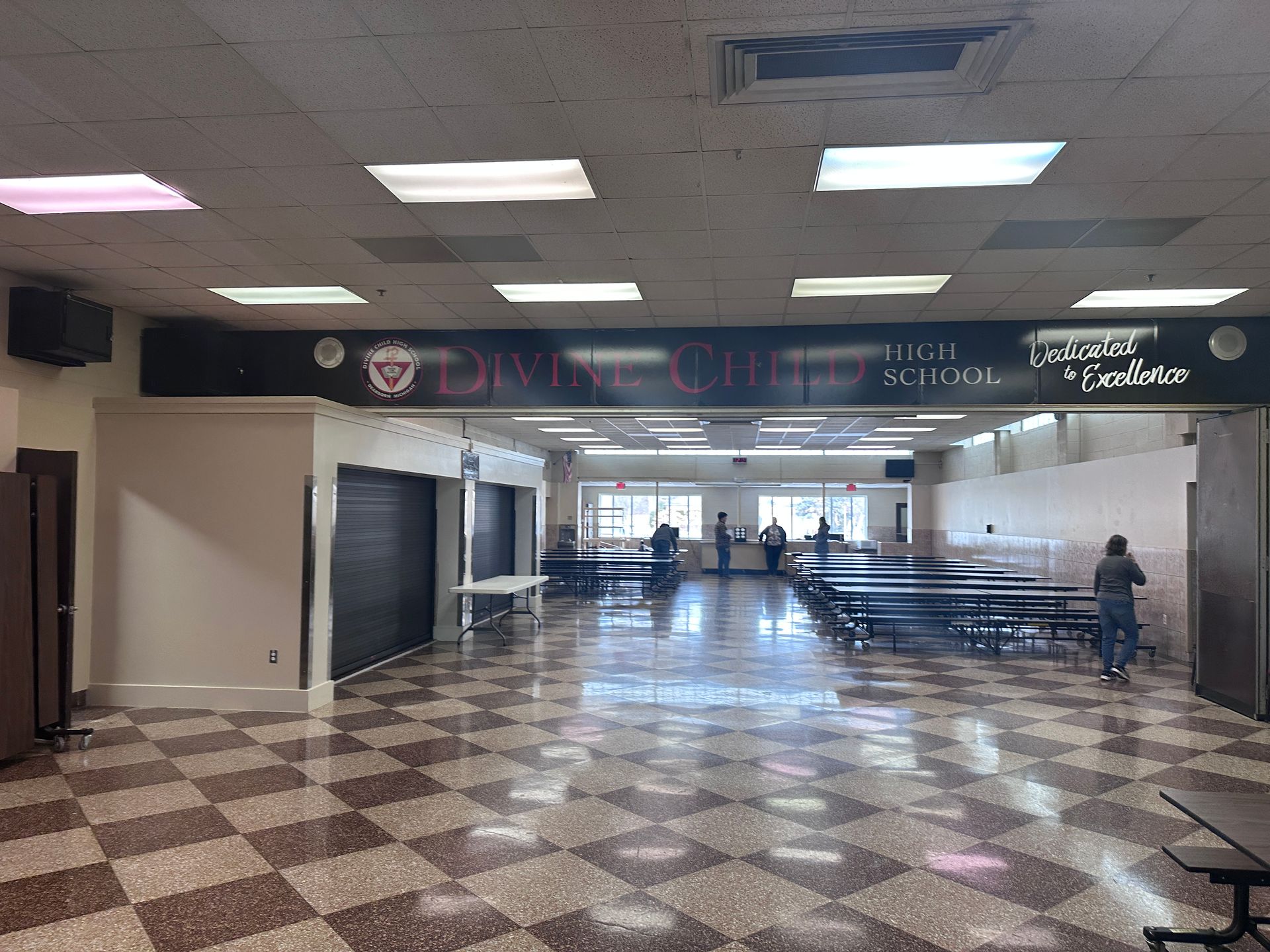 An empty, tiled room with a table, bench, and door. A garage door is visible through the window.