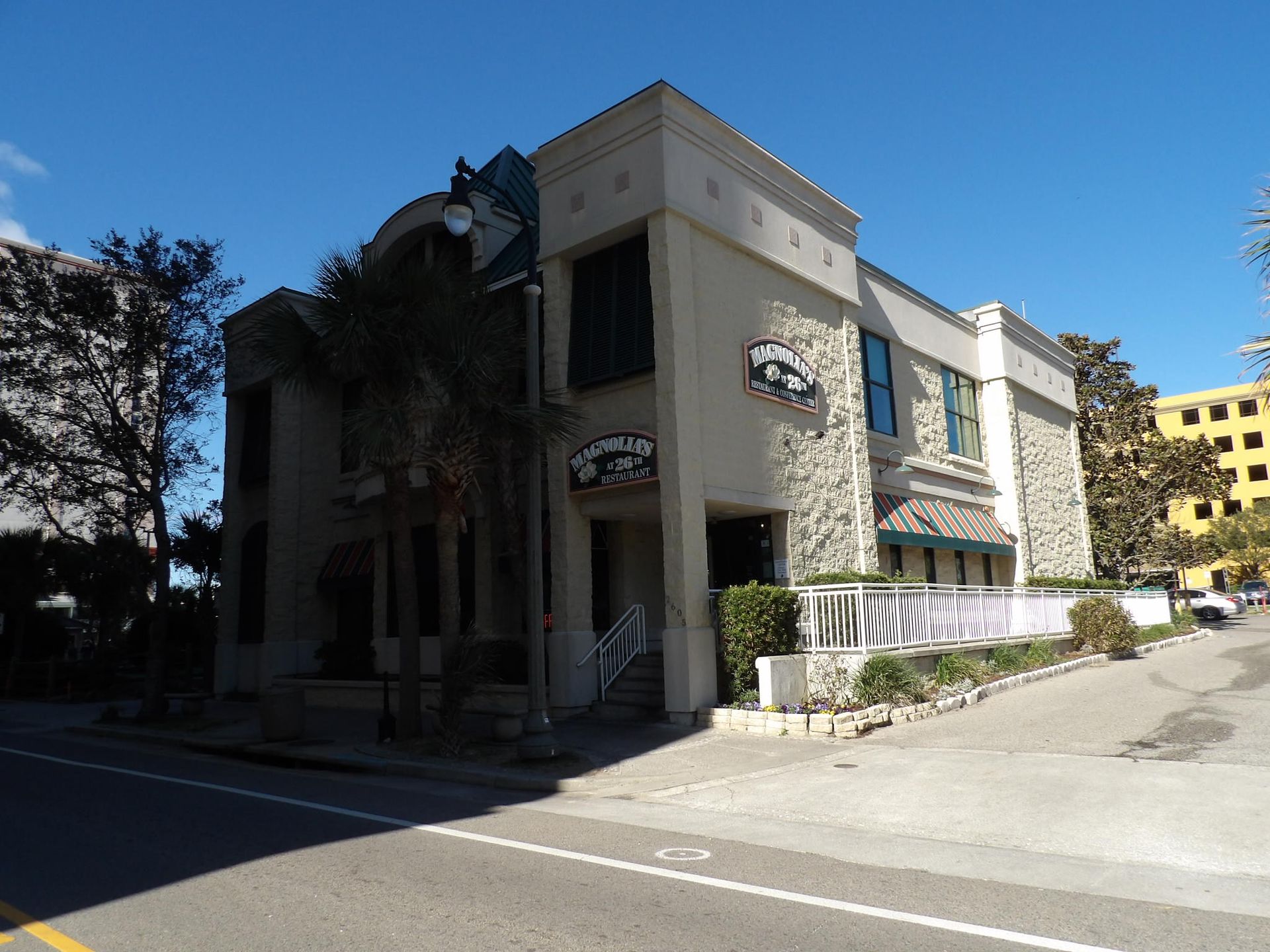 Stone building with a restaurant entrance, sidewalk, and street on a sunny day.