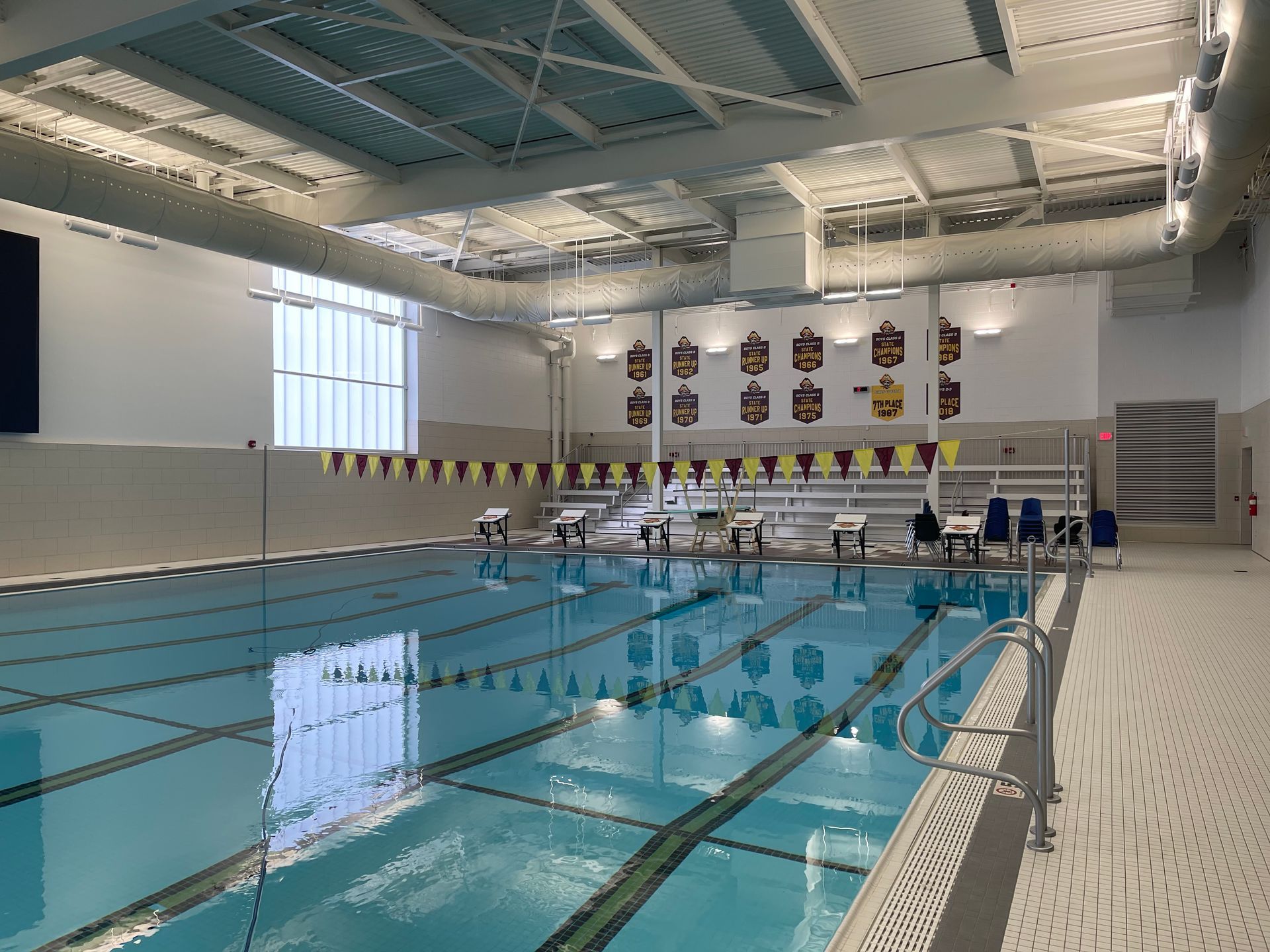 Indoor swimming pool with lanes, starting blocks, banners, and architectural details.