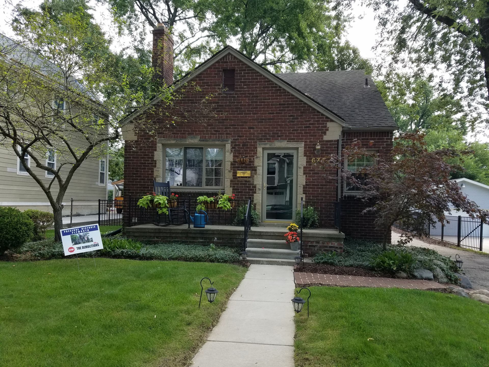 Brick house with a gray roof and small front yard, walkway leading to the front door.
