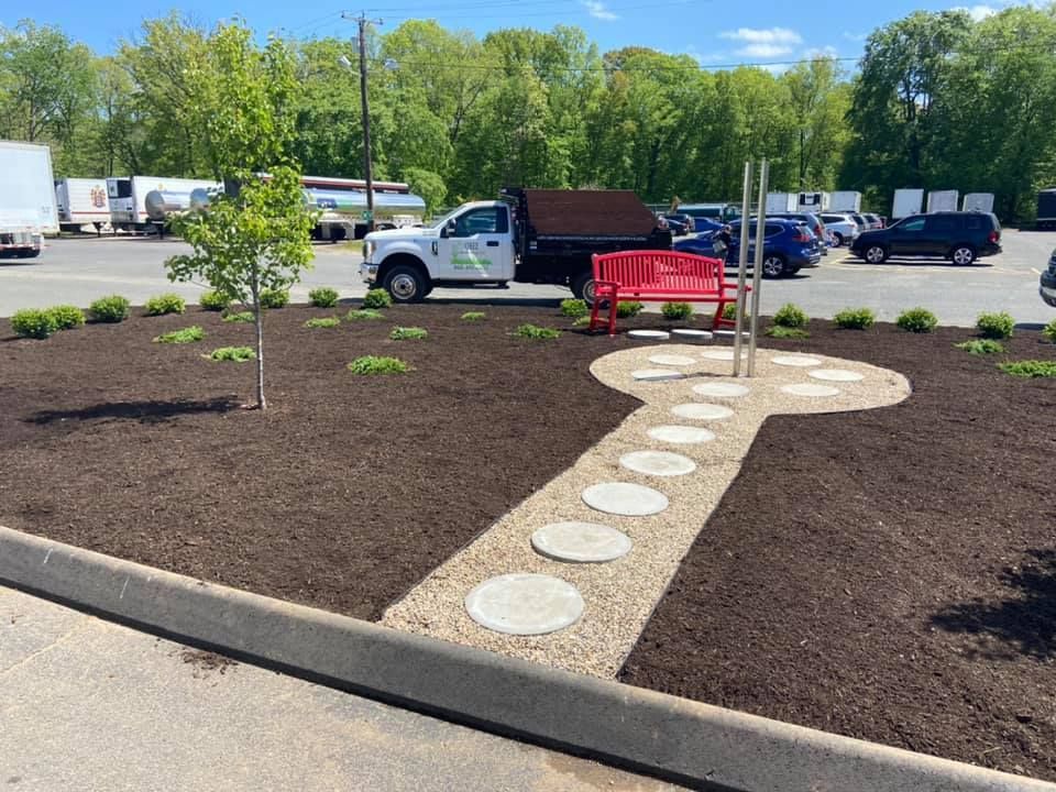 Landscaped key-shaped garden path with stepping stones, red bench, and truck in a parking lot.