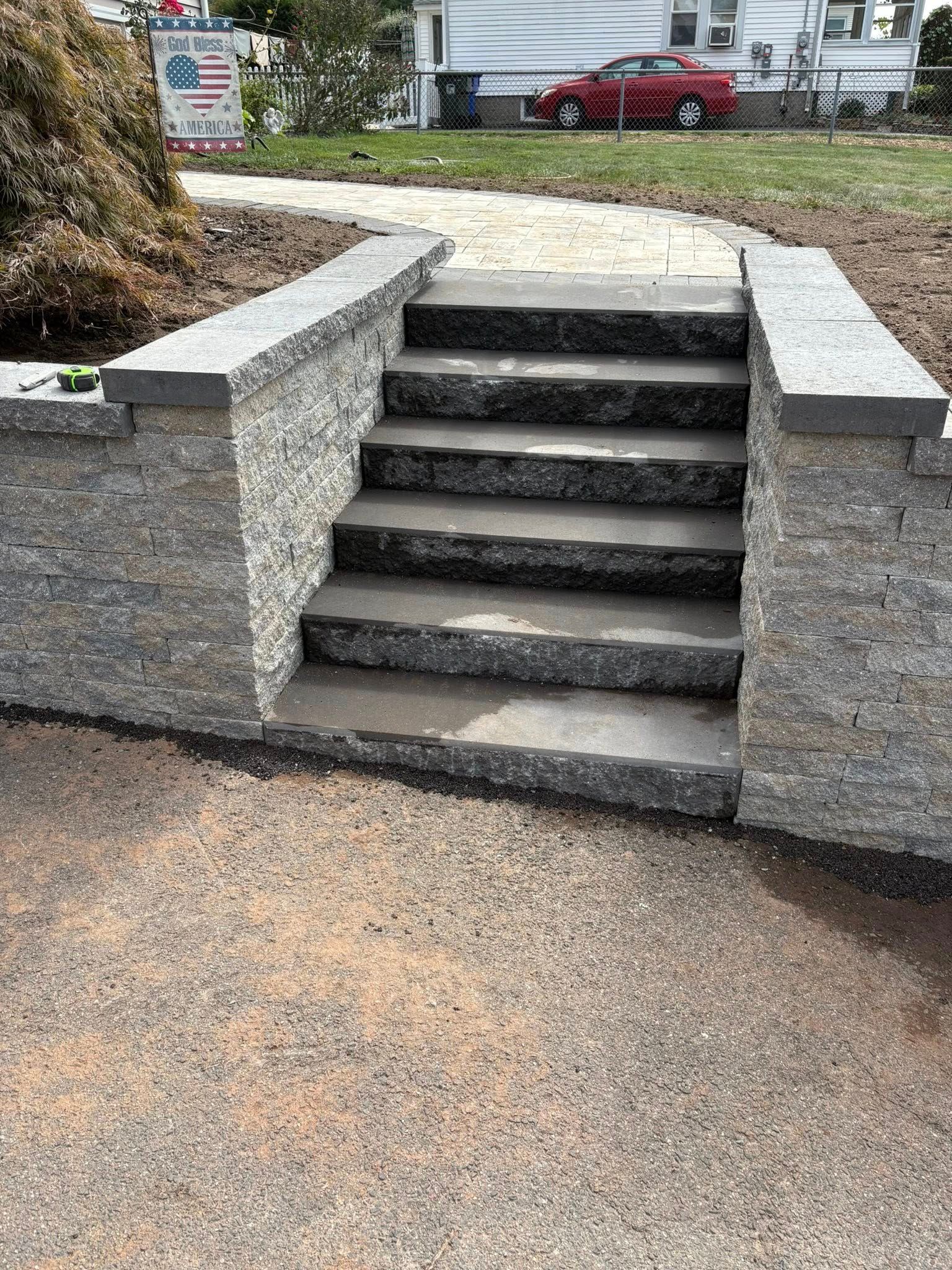 Short stone stairs with concrete side walls leading up to a yard and house
