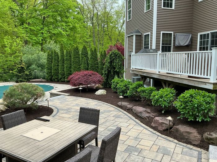 Landscaped key-shaped garden path with stepping stones, red bench, and truck in a parking lot.