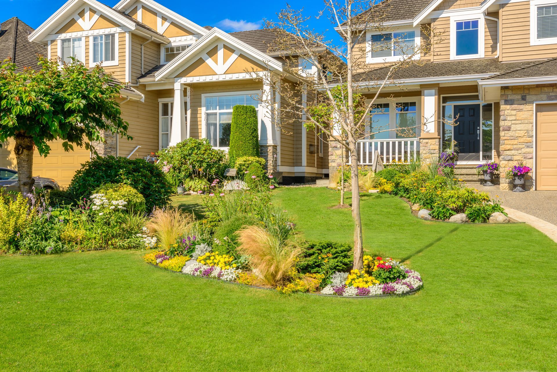 Suburban brick house with a bright green lawn, landscaped flower beds, and a front porch