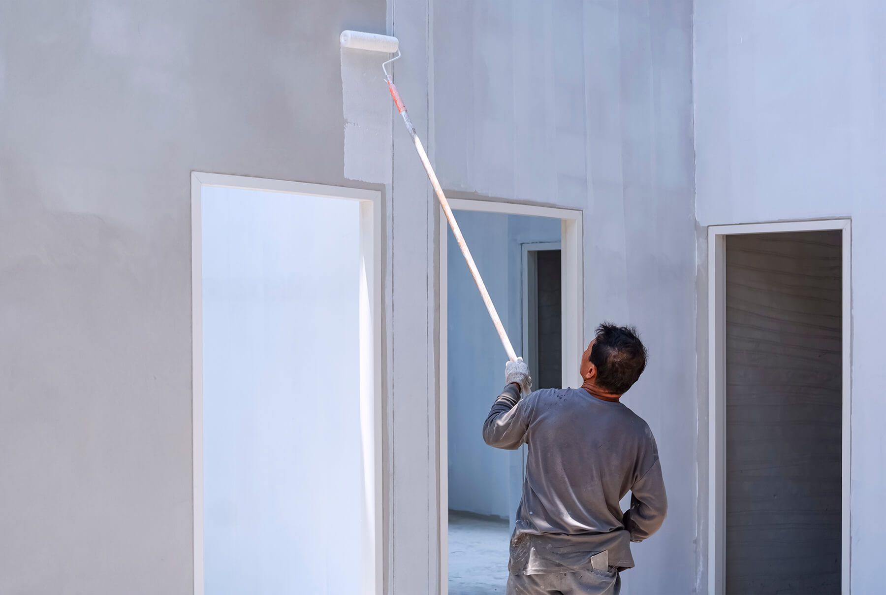 a man is painting a wall with a paint roller .
