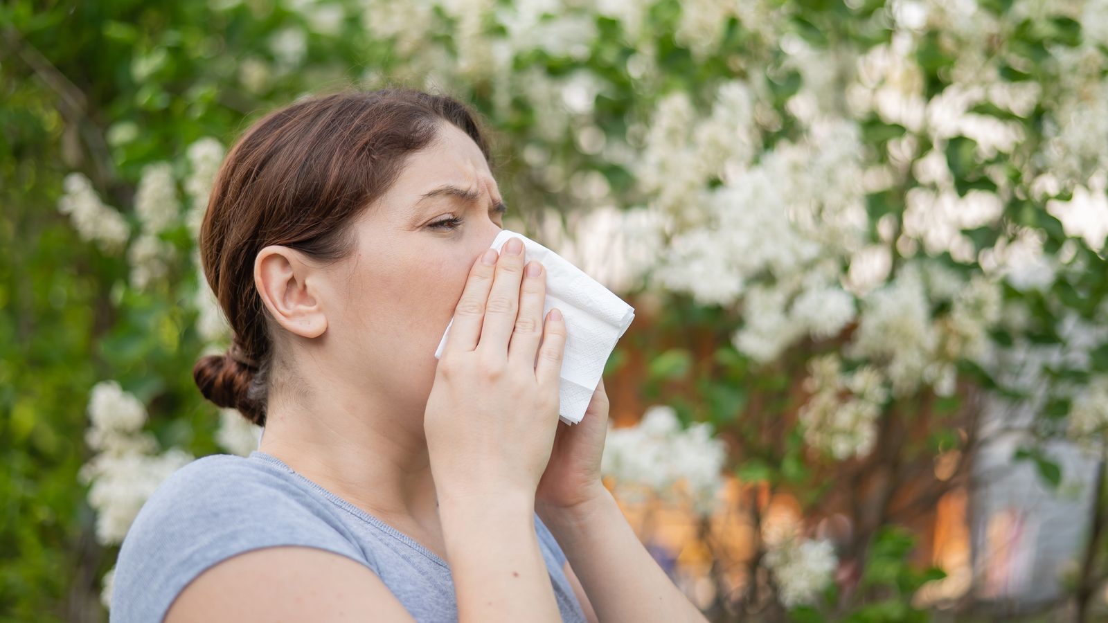 woman-suffers-from-allergies-and-blows-her-nose-into-a-napkin-while-walking-in-the-park