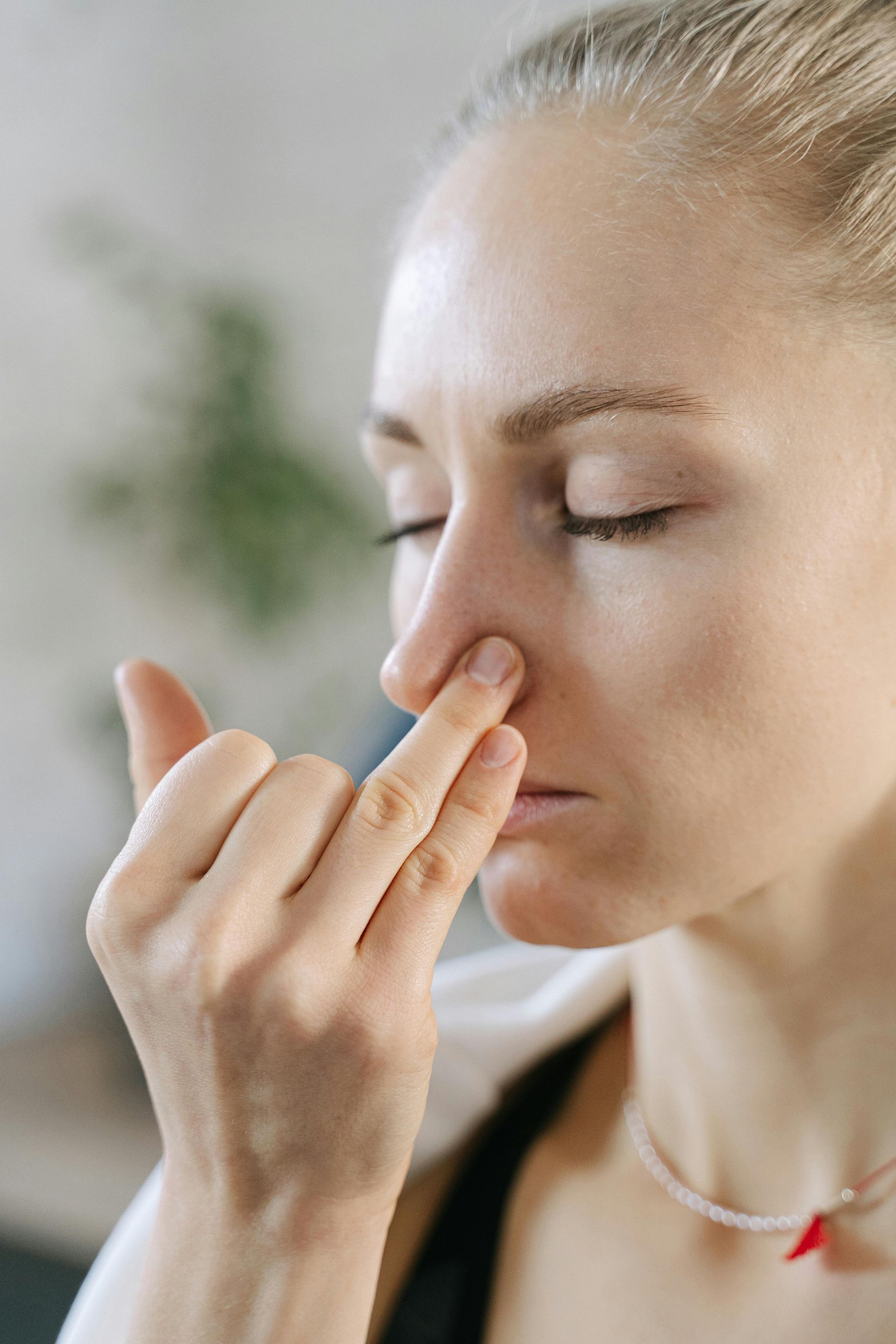 Person pinching their nose with eyes closed, suggesting discomfort or smelling something unpleasant