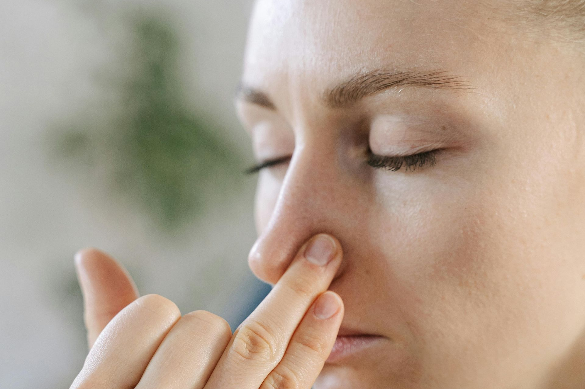Person pinching nose while closing eyes, suggesting discomfort or sensitivity