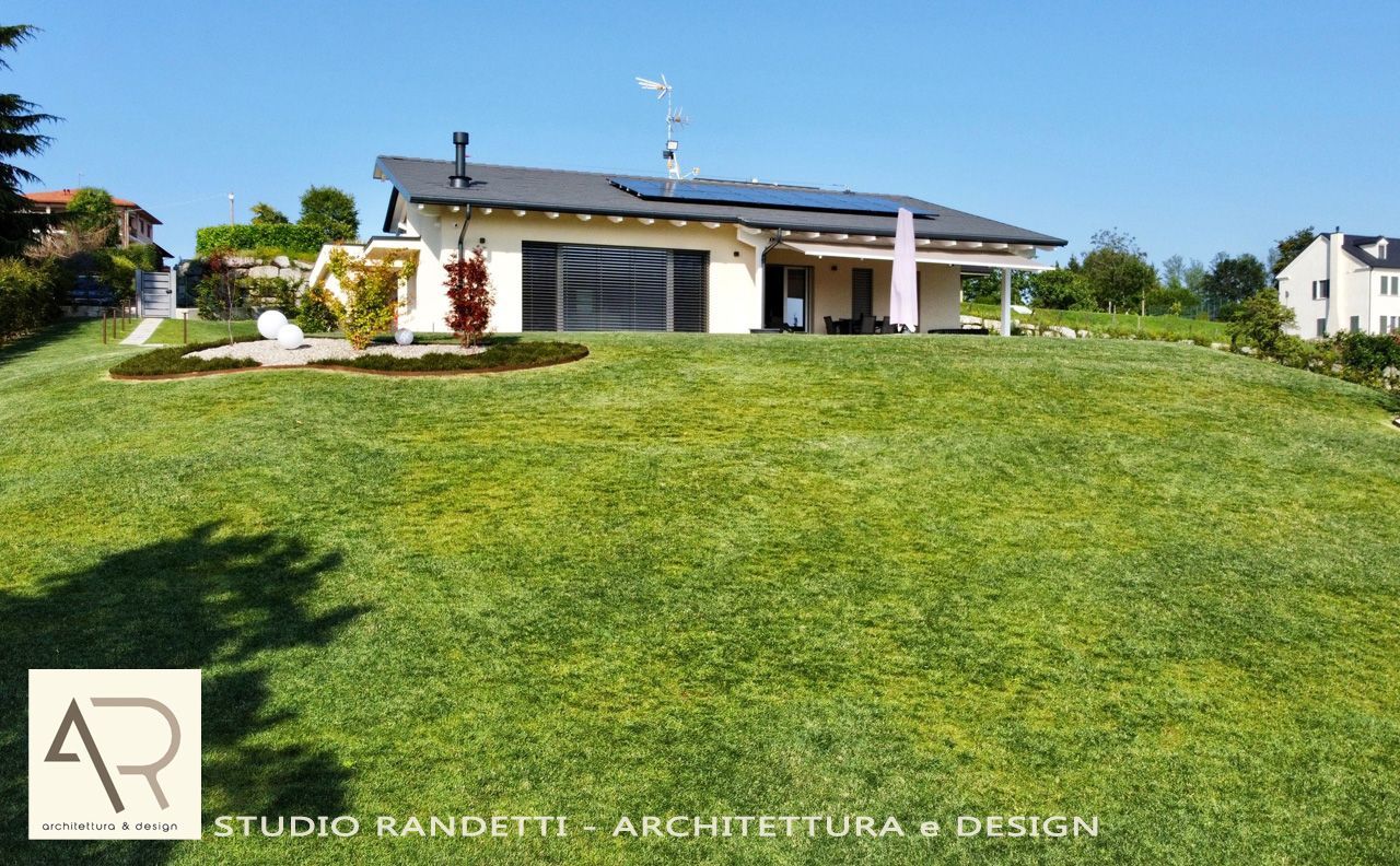 Casa moderna a un solo piano con un grande prato verde sotto un cielo azzurro brillante