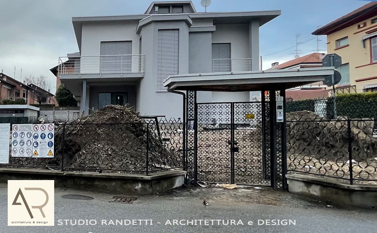 Casa moderna a due piani di colore grigio con muro in pietra e cancello in metallo nero sul davanti.