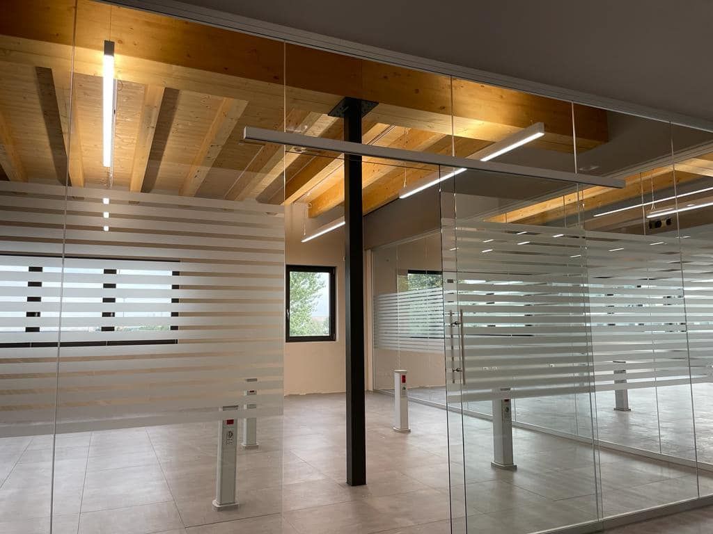 Interni di ufficio moderni con pareti divisorie in vetro, soffitto in legno e pavimento in cemento.