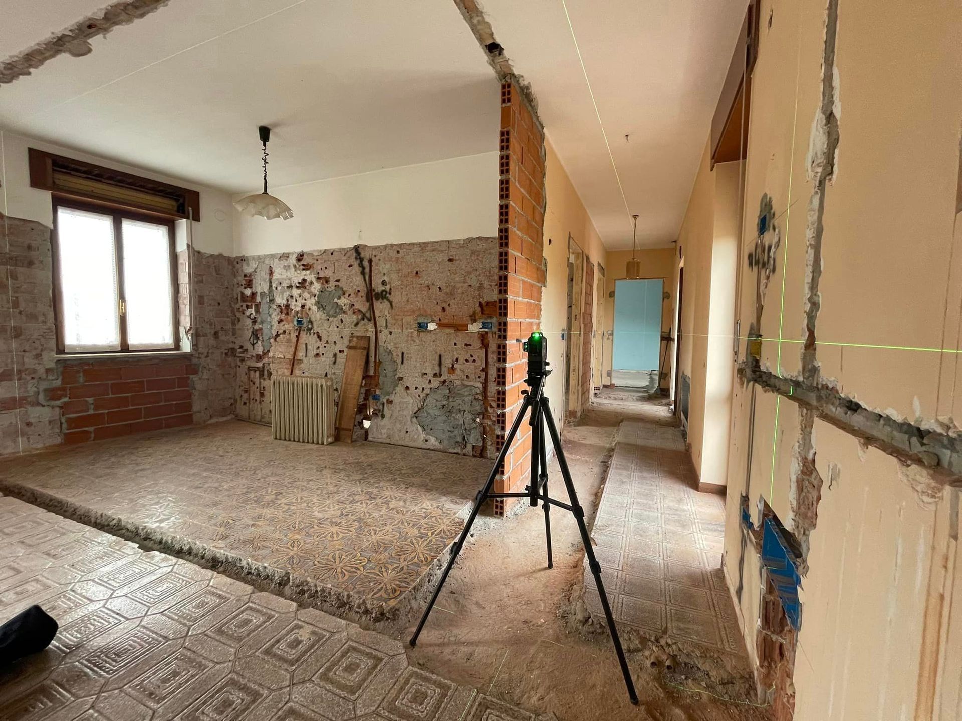 Stanza ristrutturata con pareti in mattoni a vista, treppiede e corridoio in costruzione.