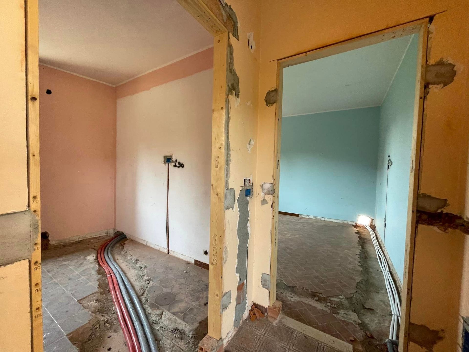 Interni ristrutturati con pareti e porta a vista e cavi a vista su un pavimento nudo.