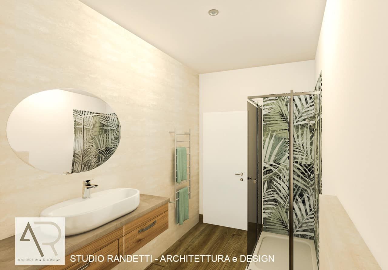 Bagno moderno con lavabo bianco, specchio rotondo, mobiletto in legno e tenda da doccia con motivo a foglie.