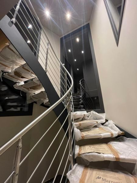 Scala crollata con detriti e ringhiera metallica penzolante all'interno di un edificio moderno, di notte.