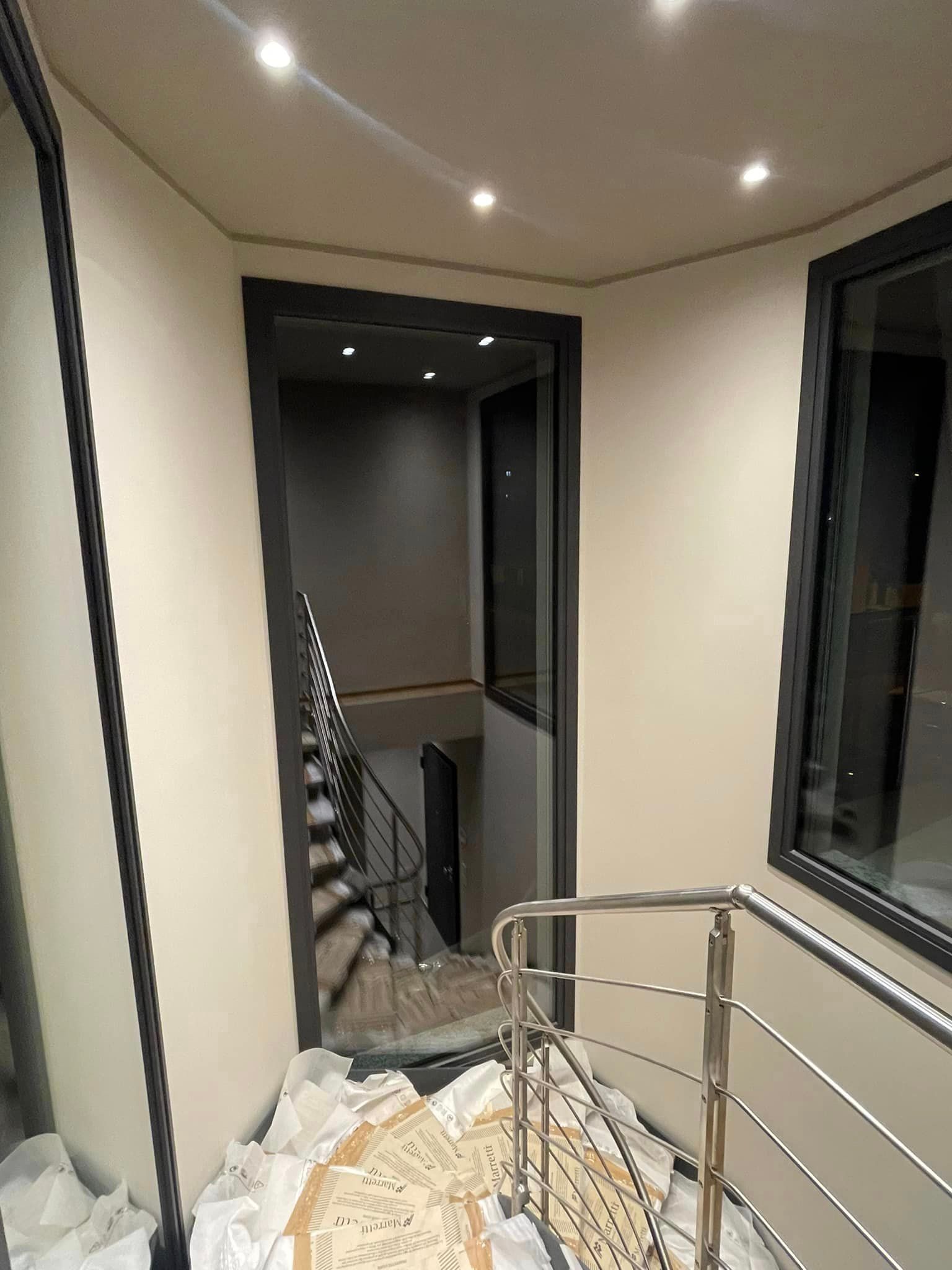 Vano scale con corrimano in metallo, pareti beige e faretti a incasso a soffitto in un interno moderno