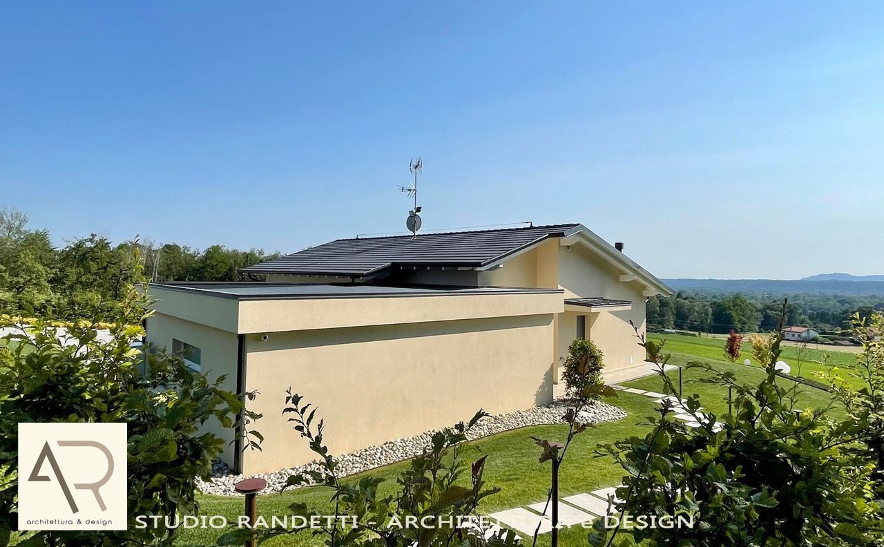 Casa moderna con pannelli solari su una collina, immersa nel verde sotto un cielo azzurro e limpido.