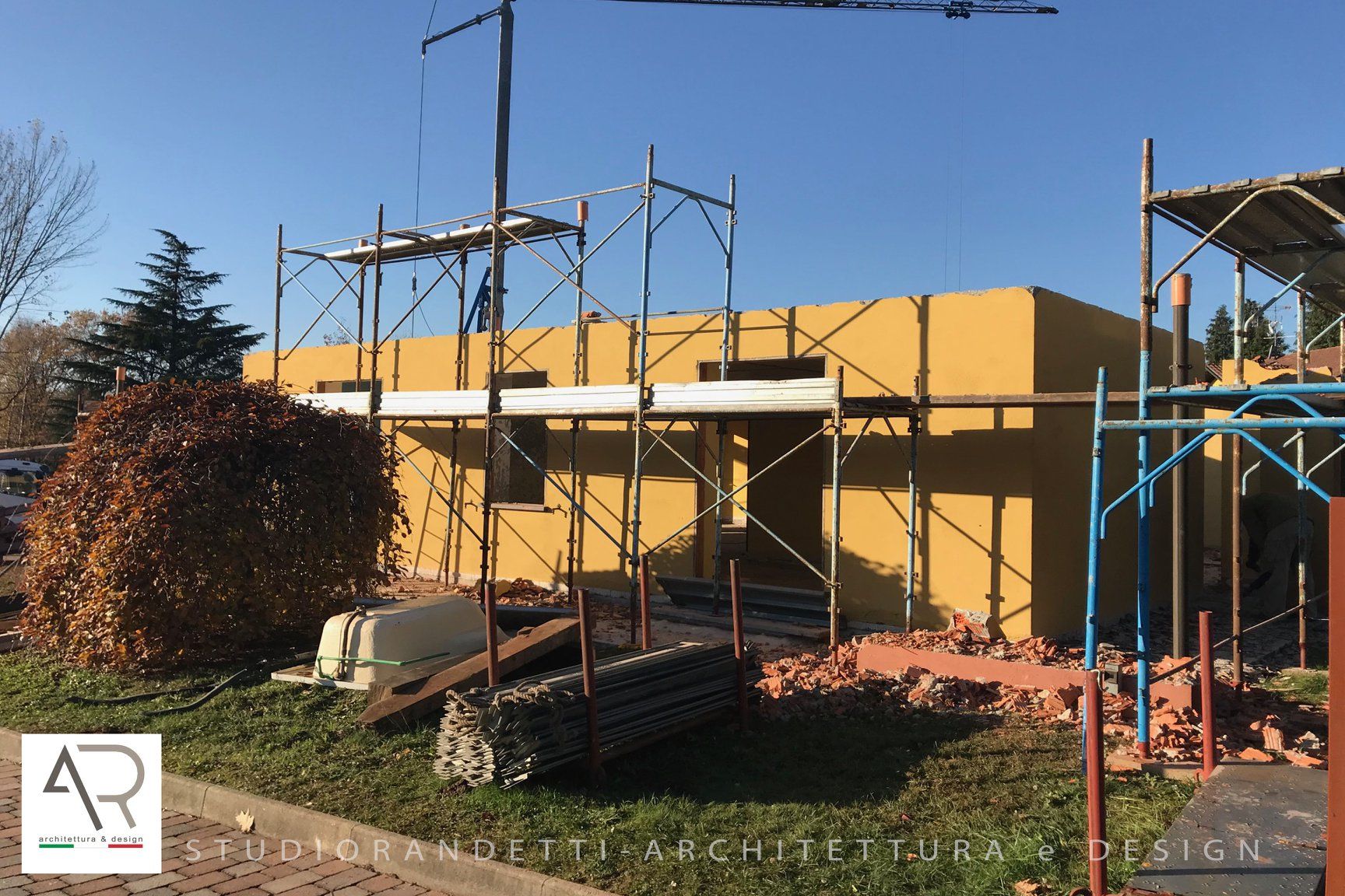 In una giornata di sole, delle impalcature circondano un edificio giallo in costruzione.