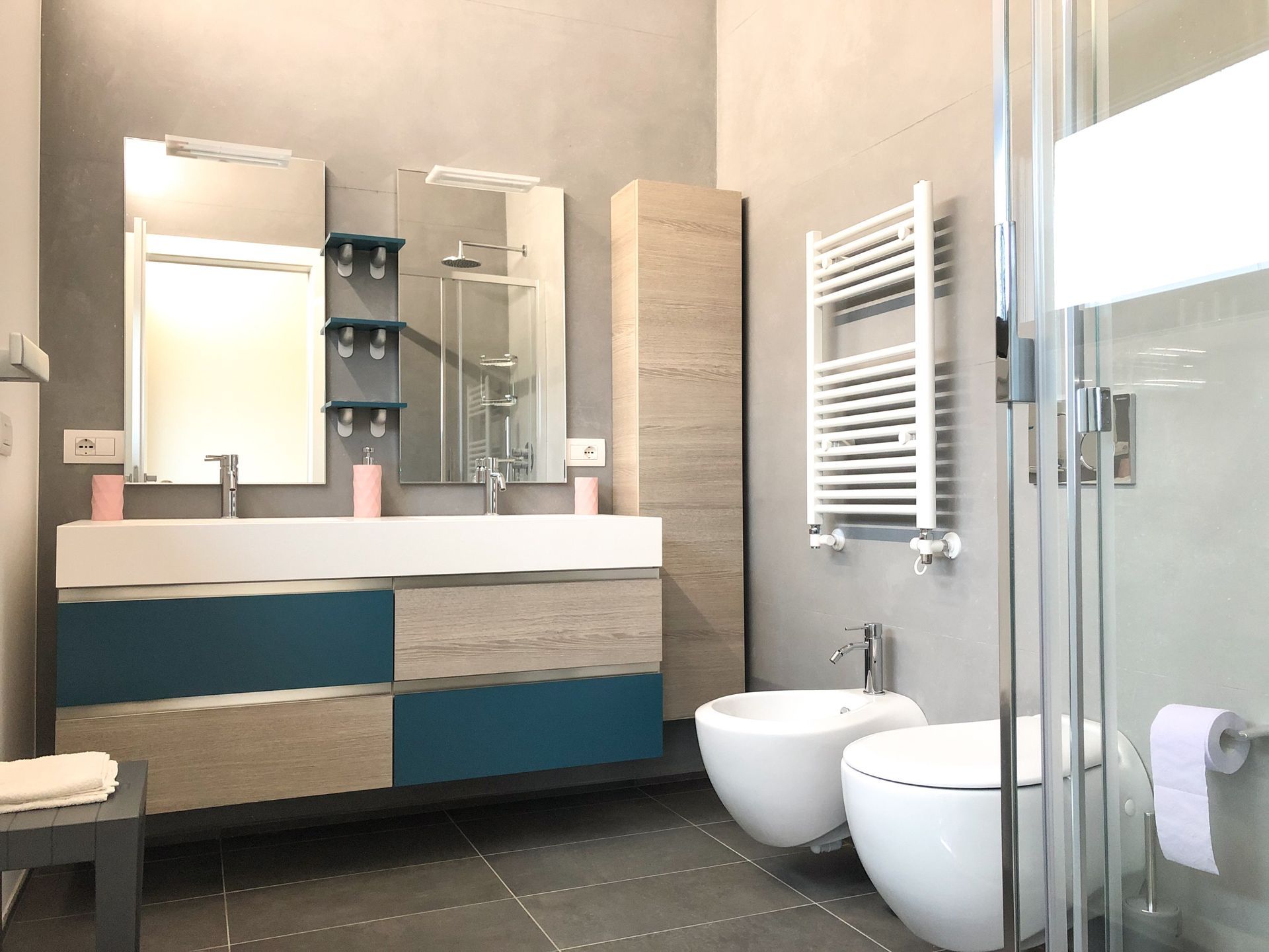 Bagno moderno con doppio lavabo, mobiletto con specchio, termoarredo e box doccia in vetro.