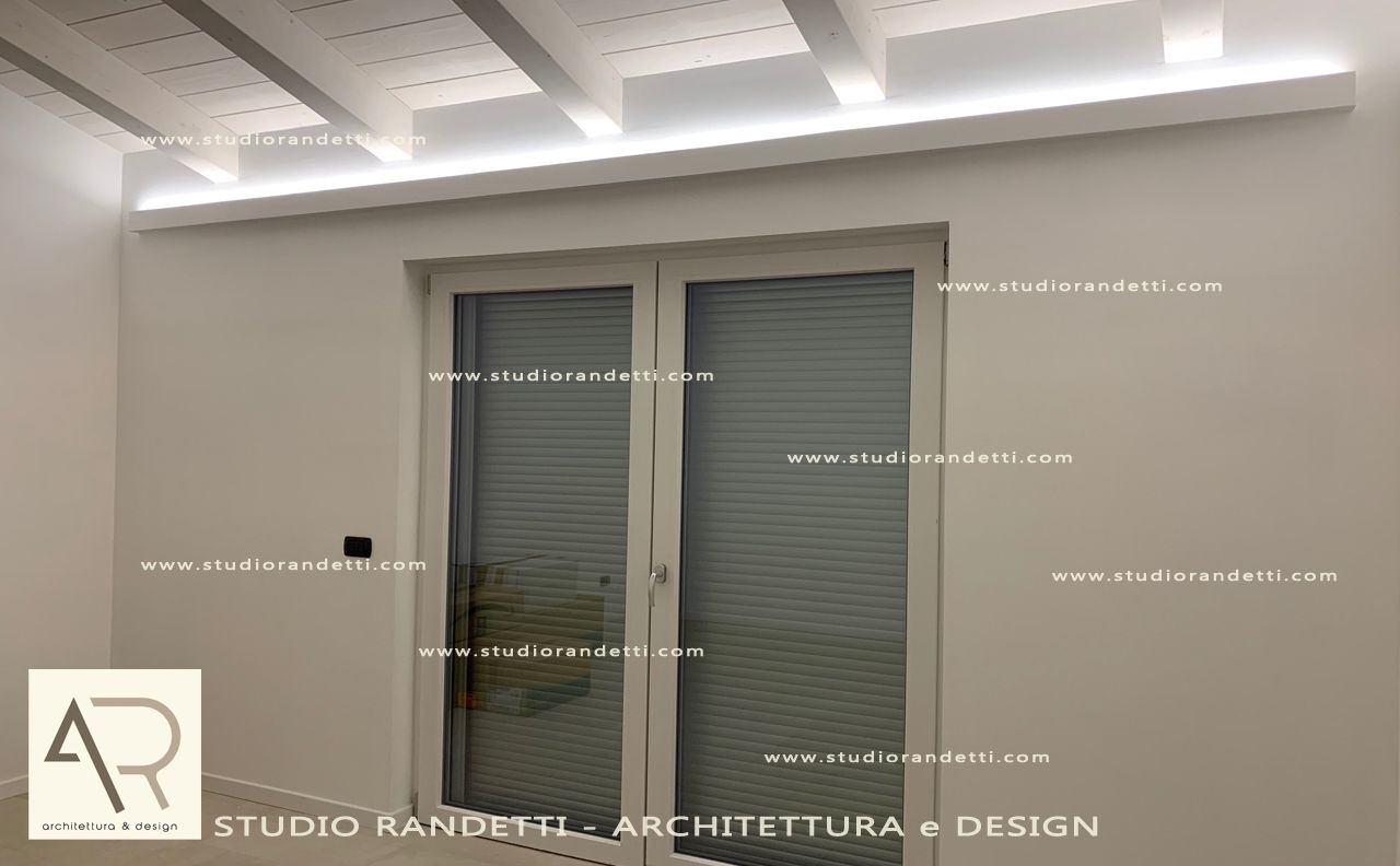 Camera da letto bianca con faretti a incasso sul soffitto, un'ampia finestra e un design moderno e minimalista.